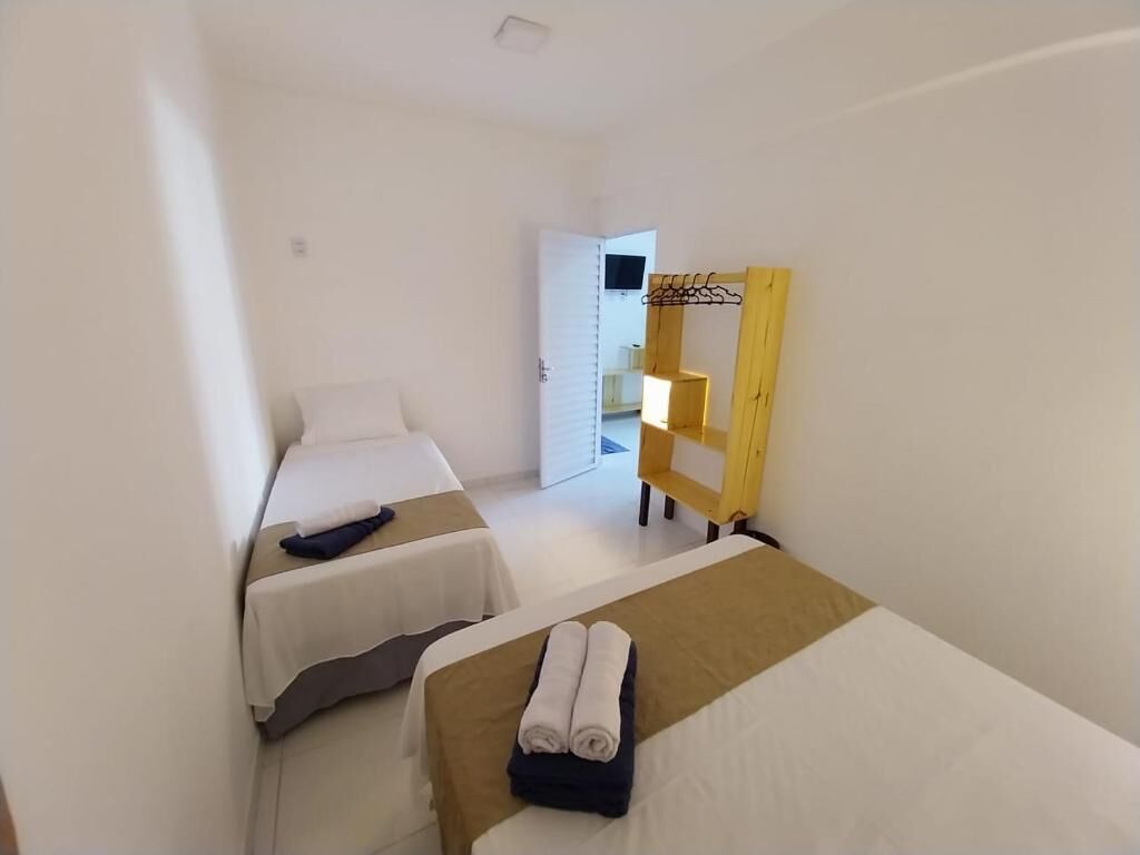A hotel room with two beds, a wooden headboard, a small table, and a TV on the wall.