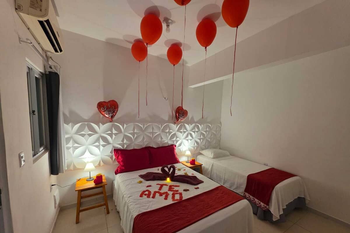 A bedroom with two beds, a decorative headboard, and red balloons.