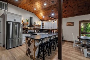 A kitchen with a central island, stainless steel appliances, and a wooden ceiling. - Gatlinburg 7BR | Swim Spa + Sauna (Gatlinburg)
