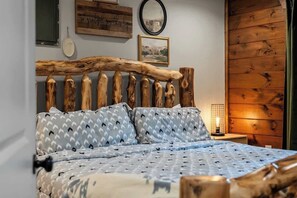 A bed with a wooden headboard, patterned pillows, and a bedside table with a lamp. - Gatlinburg 7BR | Swim Spa + Sauna (Gatlinburg)