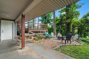 A covered outdoor area with a wooden deck, picnic table, chairs, and a fire pit. - 7-Bedroom Gatlinburg Cabin with Swim Spa, Sauna & Mountain Views (Gatlinburg)