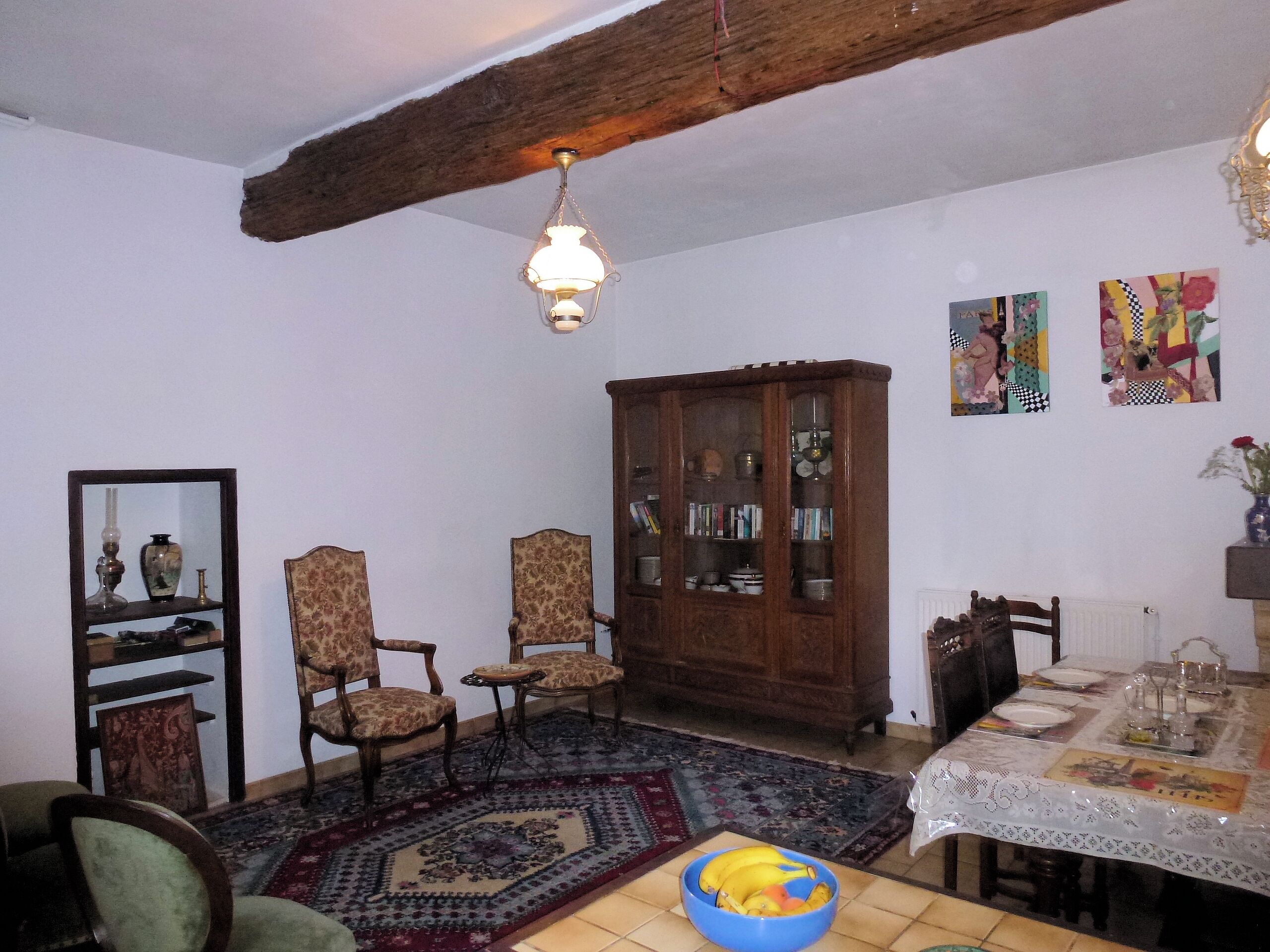 Un comedor con una mesa para cuatro, un aparador con puertas de cristal y una alfombra estampada.