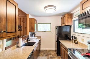A kitchen with wooden cabinets, a black refrigerator, a window, and a countertop. - Private Cabin 4BR 3BA, Fire pit, Pool table, BBQ Weber, Babbling Brook, Cornhole (Dover)