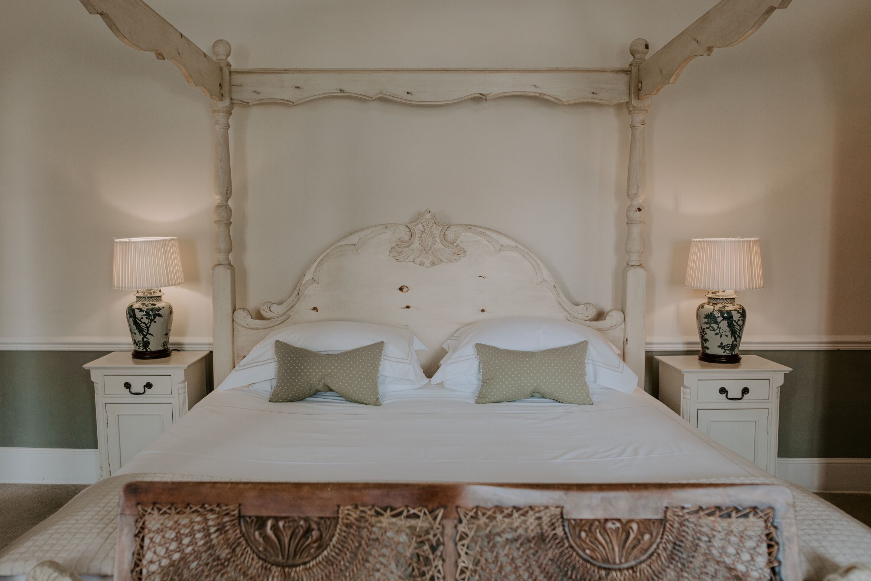 A bed with a white headboard, two bedside tables with lamps, and a decorative pillow.