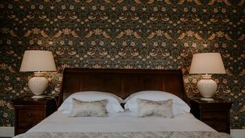 A bed with two pillows, a wooden headboard, and two bedside tables with lamps.