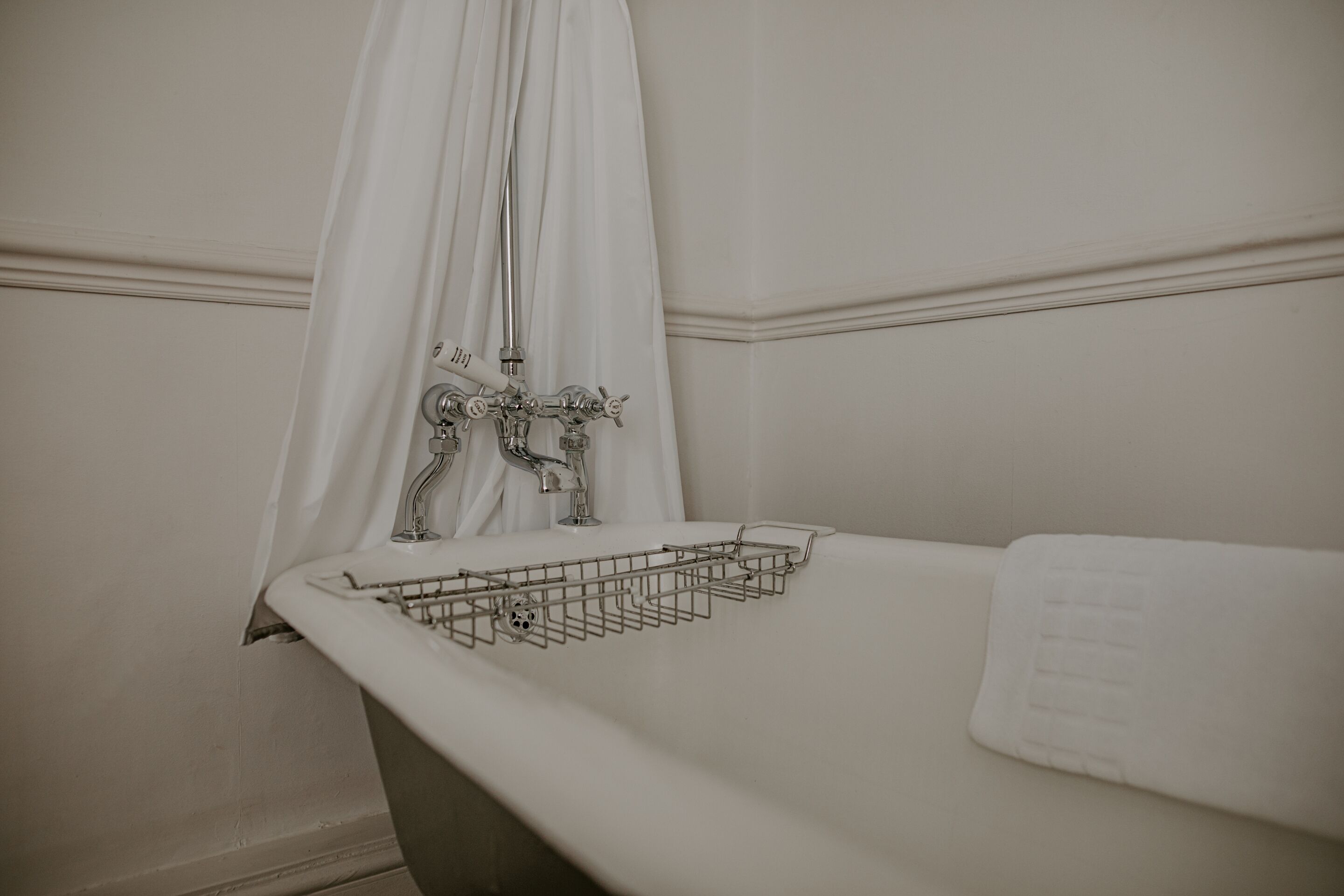 A bathroom with a bathtub, a shower curtain, and a towel rack.