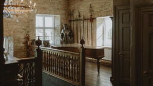 A rustic room with exposed brick walls, a wooden ceiling, a chandelier, a statue, and a window. - Allington Manor (Allington)
