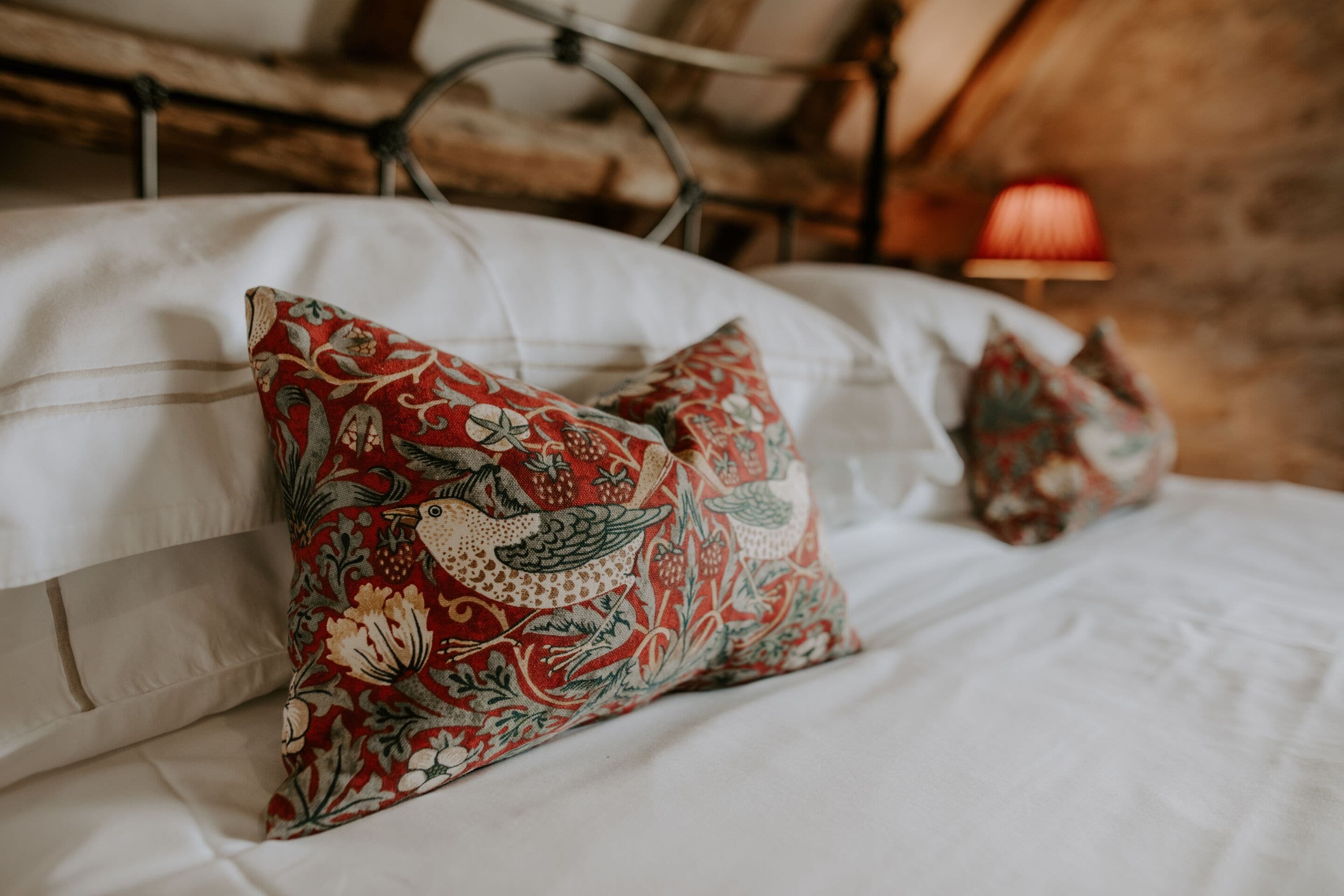 Un lit avec du linge de lit blanc et des coussins décoratifs ornés de motifs floraux.