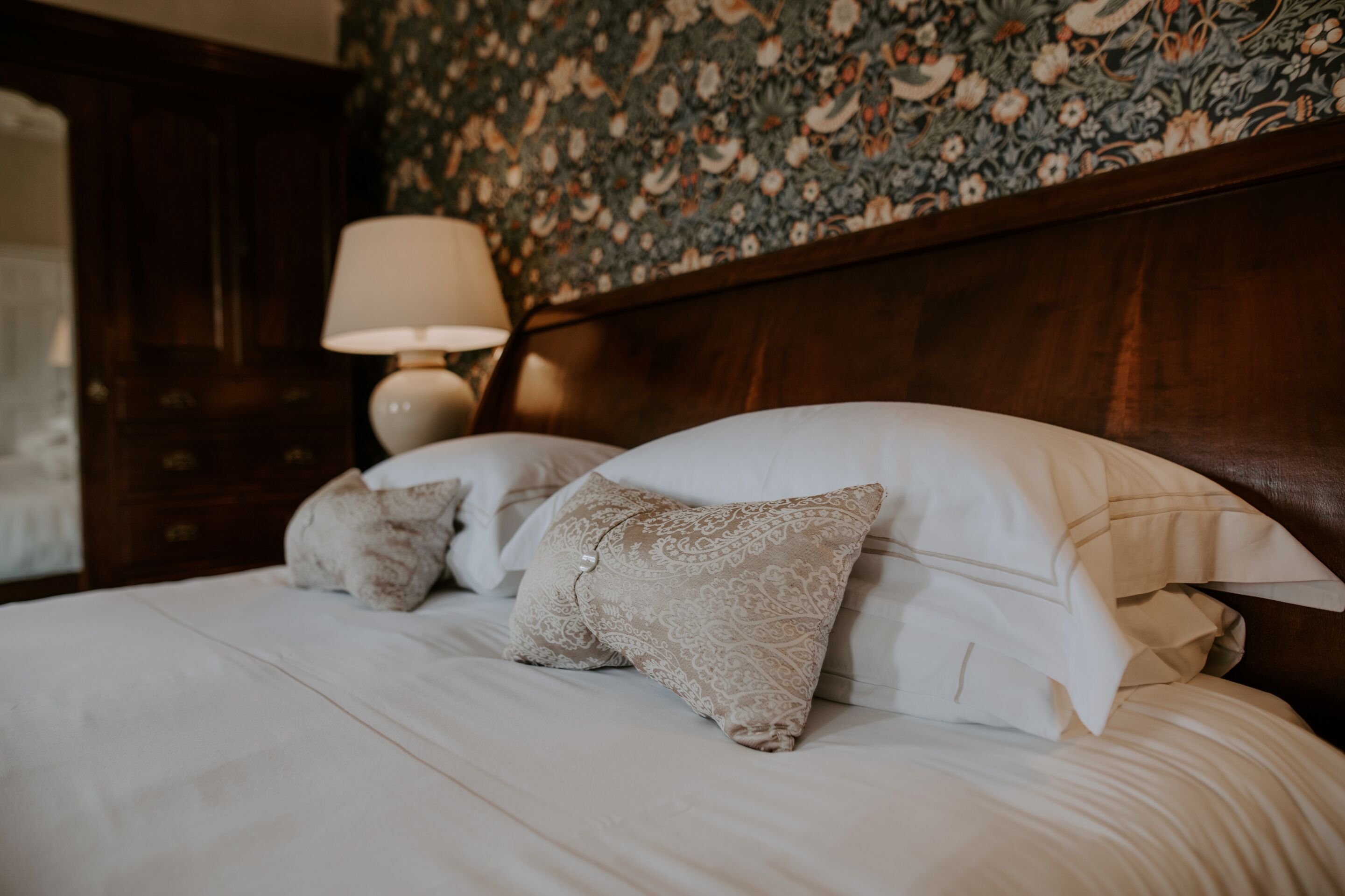 A neatly made bed with white bedding and decorative pillows.