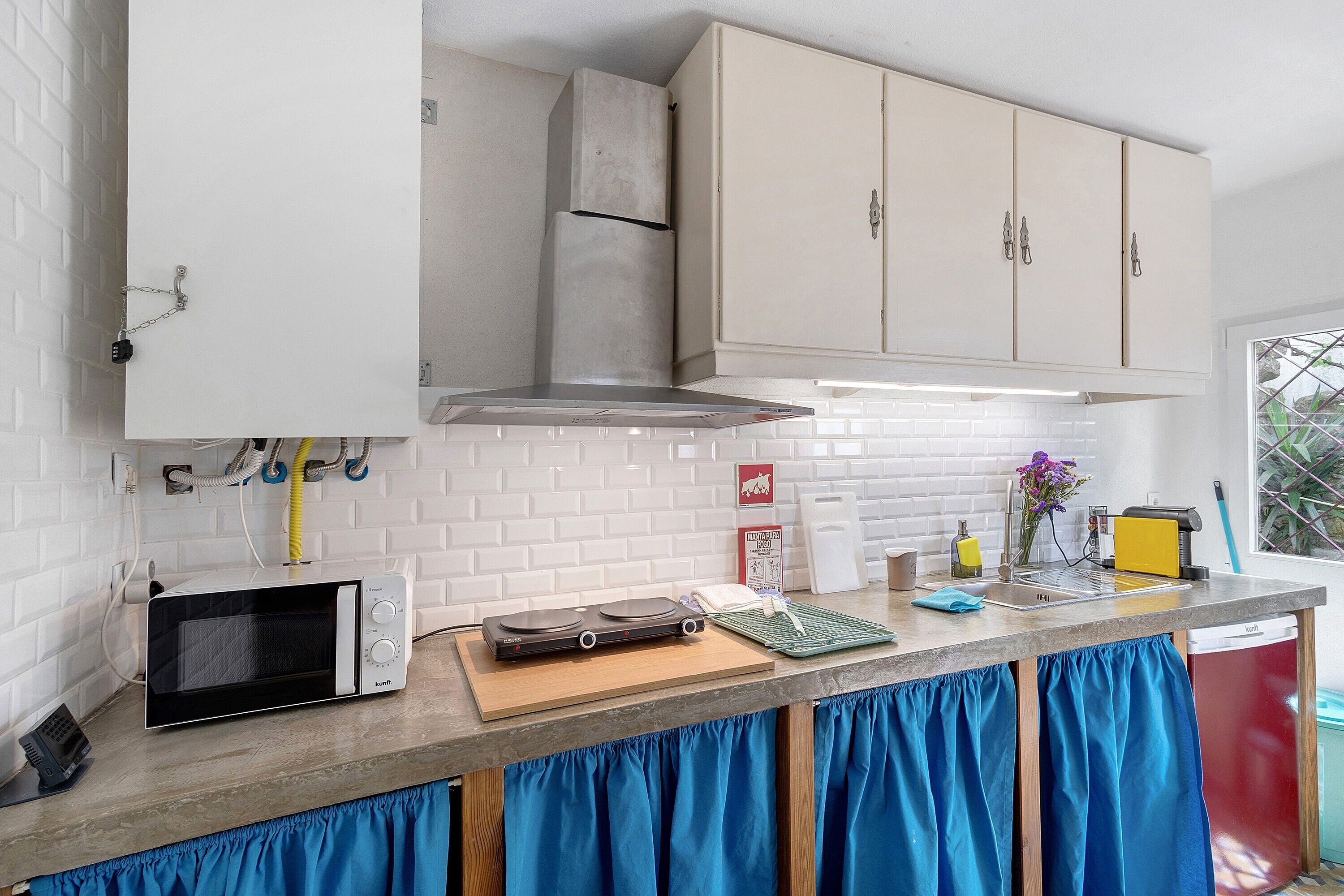 A kitchen with a microwave, toaster, and a small countertop with a cutting board and a green mat.