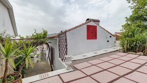 A rooftop terrace with a red door, potted plants, and a checkered tile pattern. - Portas de Caminha III Studio with Shared Terrace, Balcony and Wi-Fi (Caminha)