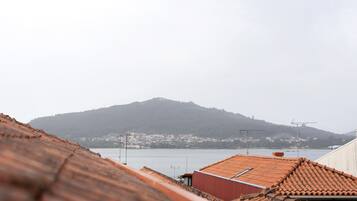 Vista de una colina con un edificio en la cima, una masa de agua y un tejado de baldosas al frente.