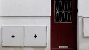 Puerta roja con el número '139' sobre ella, pared blanca y dos armarios blancos con tiradores decorativos.