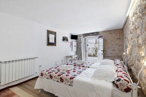Ein Schlafzimmer mit einem Bett, weißen Wänden, einer Heizung und einer Steinwand.