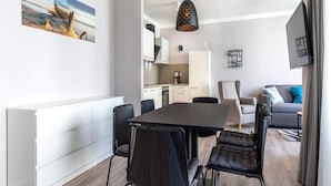 A modern living space with a dining area, kitchen, and seating area. - Seaside Comfort Travemunde Stay (Lübeck)