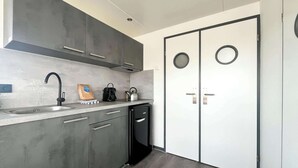 A modern kitchen with grey cabinets, a stainless steel sink, a kettle, and a black dishwasher. - Houseboat for 4 on Uitgeester Lake (Uitgeest)