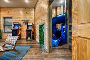 A wooden interior with a play area, including a slide and arcade games.