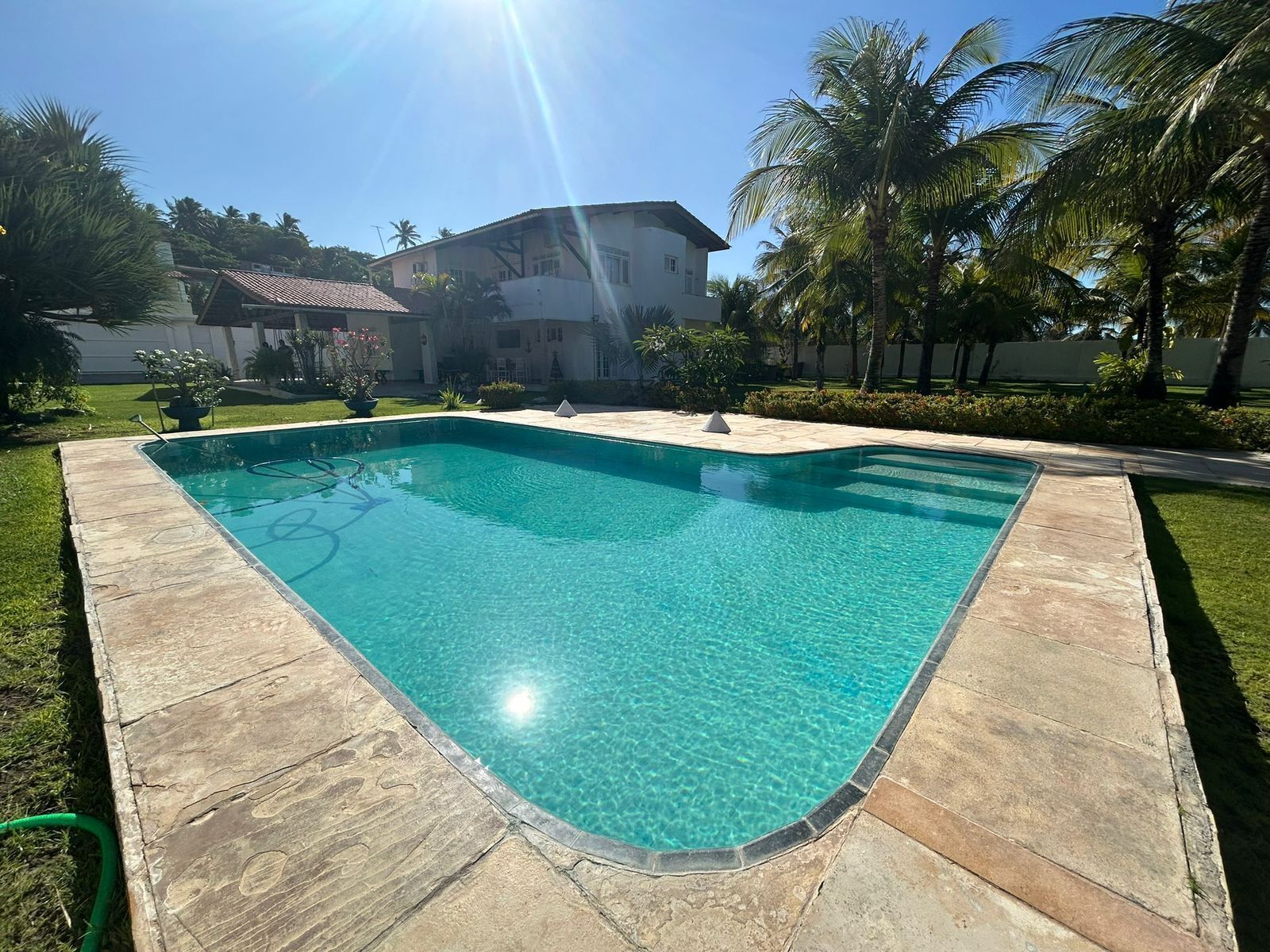 Una piscina rectangular con agua cristalina azul, rodeada por una terraza de piedra.