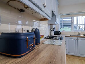 A modern kitchen with a gas stove, cabinets, and a window. - Sea Lovers (Exmouth)