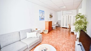 Una sala de estar moderna con un sofá gris, una mesa de centro, una planta y un cuadro en la pared.