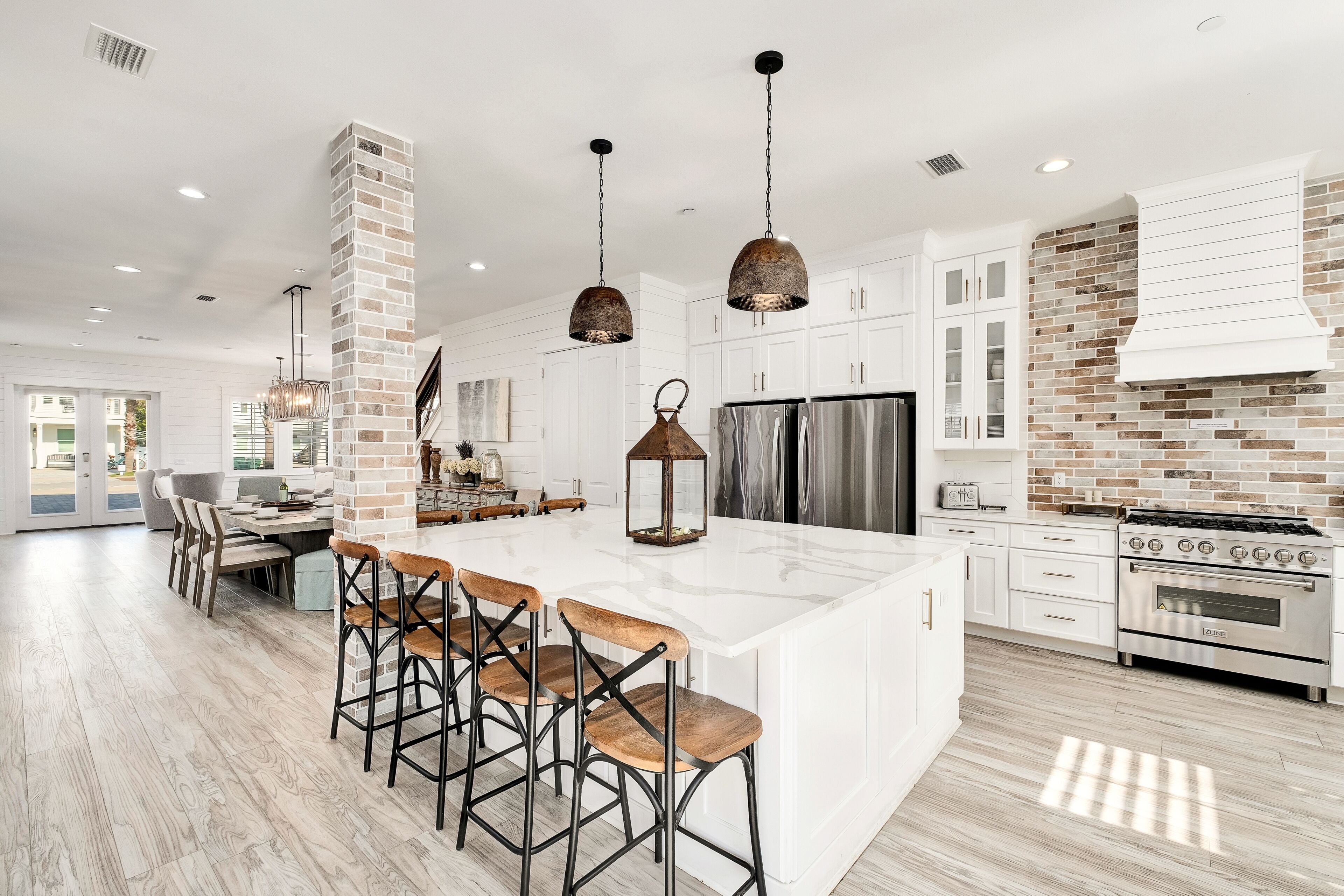 A modern kitchen with a large island, bar stools, a stove, and a refrigerator.