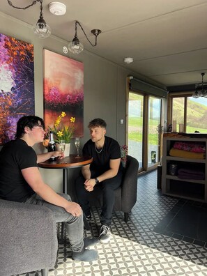 A modern interior with a round table, two chairs, a vase with flowers, and a painting on the wall. - Mountain Hidaway next to a Pool (Talerddig)