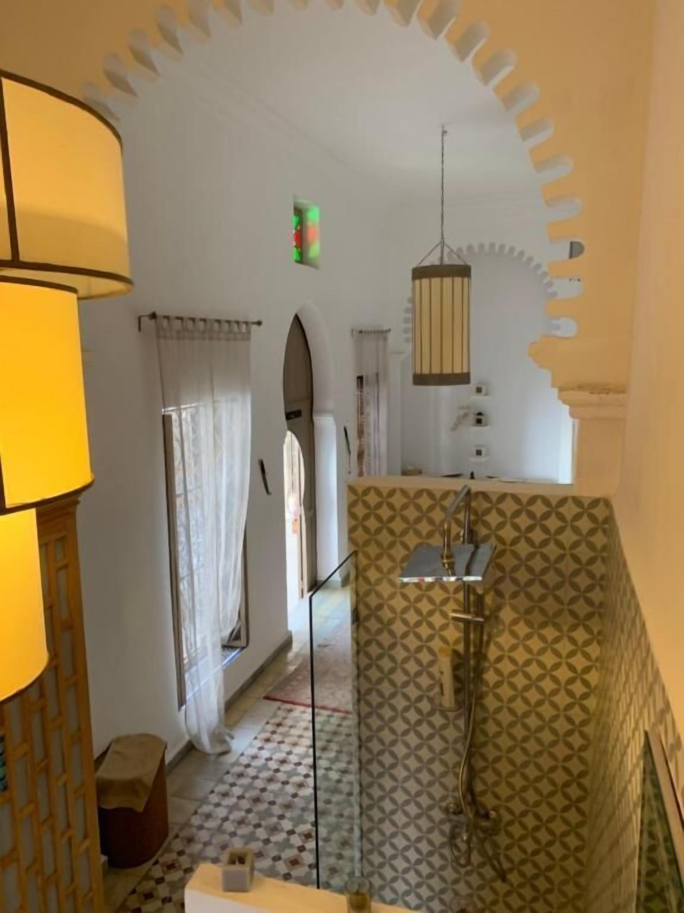A bathroom with a patterned shower wall, a hanging light fixture, and a visible shower control.