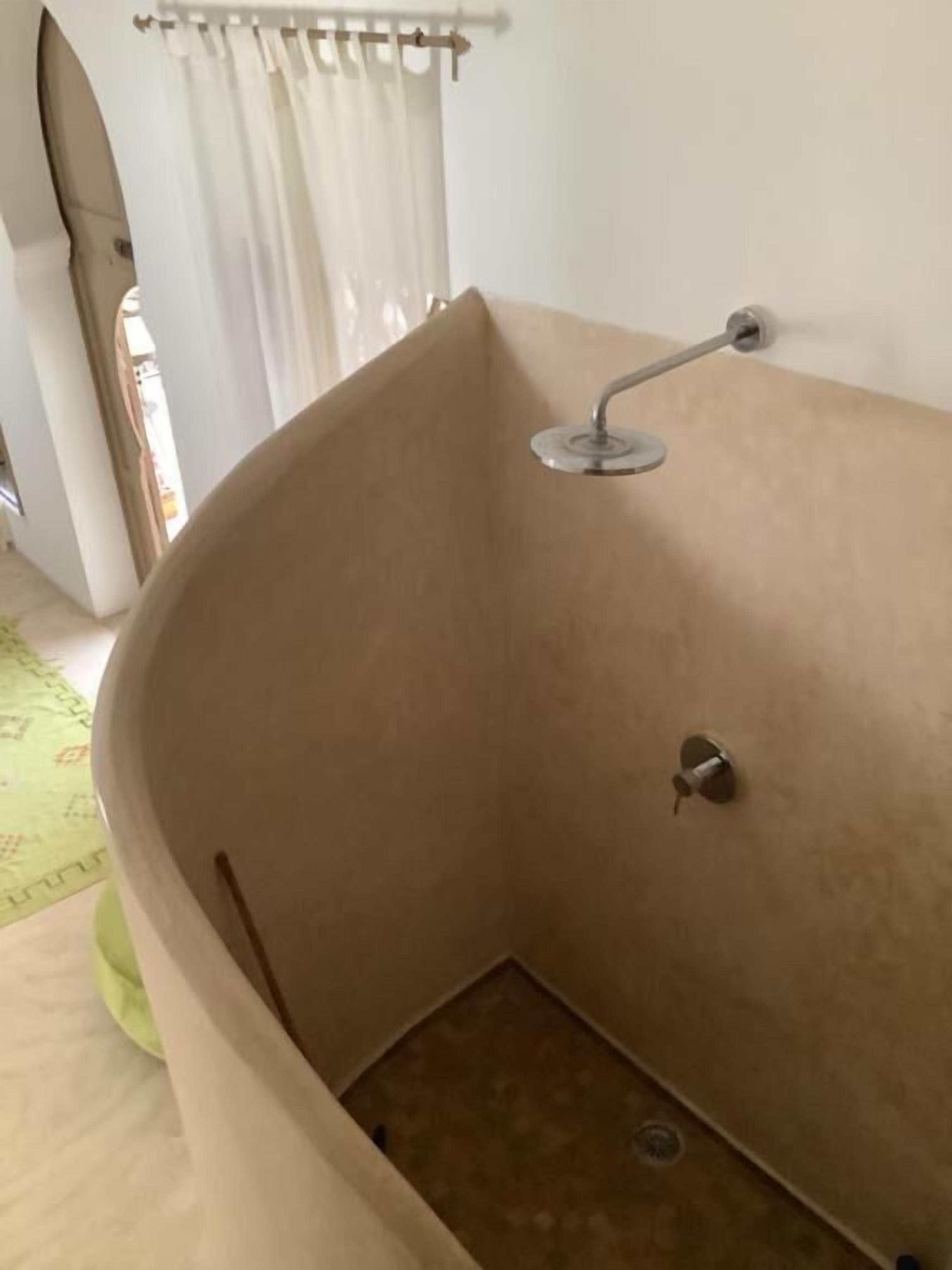 A corner bathtub with a showerhead, a towel rack, and a visible drain.