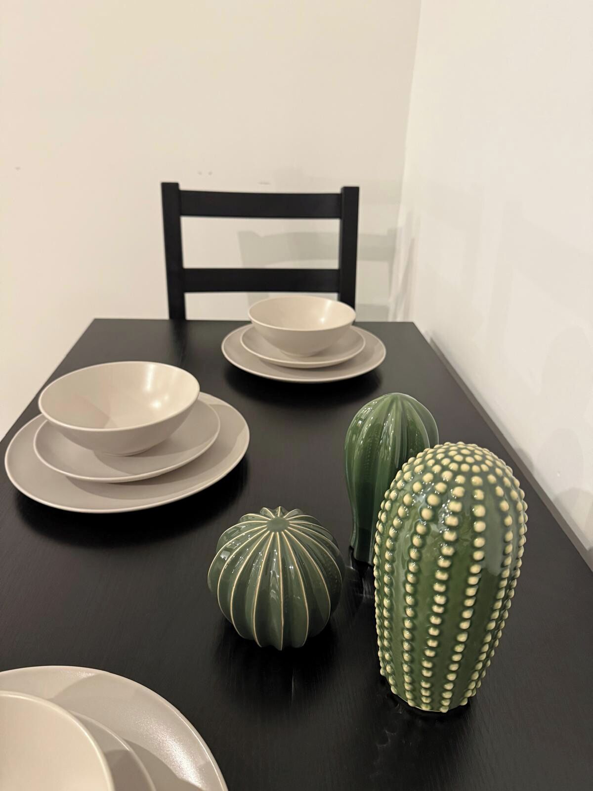 A dining table with plates, bowls, and decorative vases.