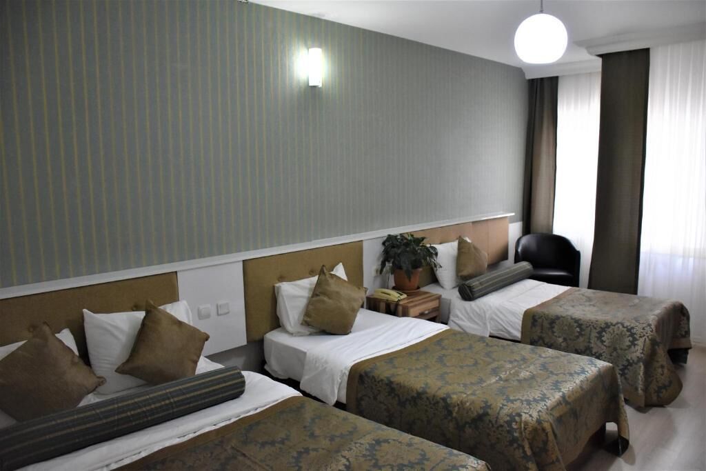 A hotel room with two beds, a nightstand, a chair, and a potted plant.