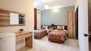 A hotel room with two beds, a desk, a refrigerator, and a mirror. - Dınar Hotel (Istanbul)
