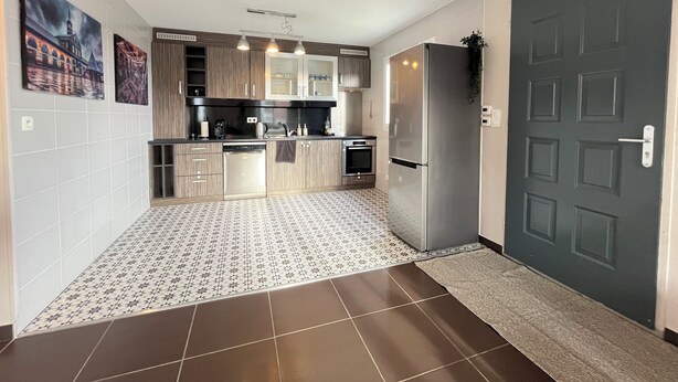 A modern kitchen with a built-in oven, refrigerator, and a microwave. There is a tiled backsplash and a wooden countertop. - Modern house with terrace and parking. Overlooking the city (Clermont-Ferrand)