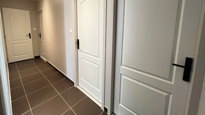 A hallway with two white doors, a light switch, and a tiled floor. - Modern house with terrace and parking. Overlooking the city (Clermont-Ferrand)