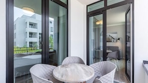 A balcony with a table and chairs, large windows, and a view of a building. - 4 Star Holiday Home in Travemunde (Lübeck)