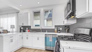 Una cucina moderna con mobili bianchi, un piano cottura in acciaio inossidabile e una lavastoviglie.