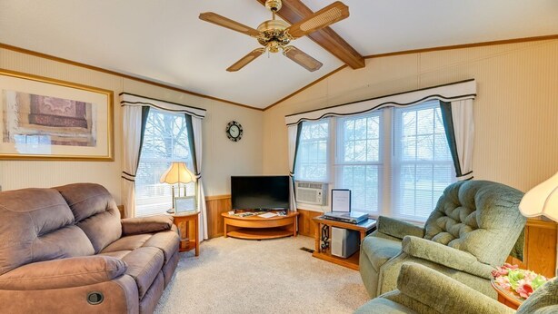 A living room with a ceiling fan, a television, a fireplace, and two armchairs. - Serene Getaway Centrally Located in the FLX (Dundee)