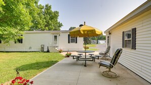 A patio with a table and chairs, a yellow umbrella, and a flower bed. - Serene Getaway Centrally Located in the FLX (Dundee)
