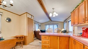 A kitchen with wooden cabinets, a central island, a dining table with chairs, and a clock on the wall. - Serene Getaway Centrally Located in the FLX (Dundee)
