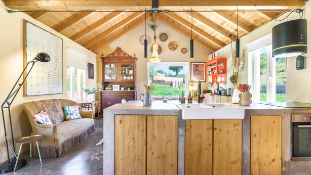 A kitchen with wooden cabinets, a central island, and a hanging light fixture. - Holiday Home 'Eclectic Monte Laginha Alentejo' with Private Pool, Terrace & Wi-Fi (Lajinha)