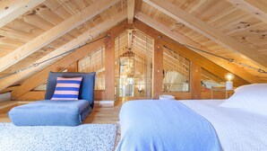 An attic bedroom with a sloped ceiling, a bed, a chair, and a small table. - Holiday Home 'Eclectic Monte Laginha Alentejo' with Private Pool, Terrace & Wi-Fi (Lajinha)