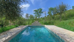 A rectangular swimming pool with a geometric structure in the center, surrounded by lush greenery and trees. - Holiday Home 'Eclectic Monte Laginha Alentejo' with Private Pool, Terrace & Wi-Fi (Lajinha)