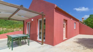 Een rood gebouw met een overdekte patio, een tafel met stoelen en een heldere lucht.