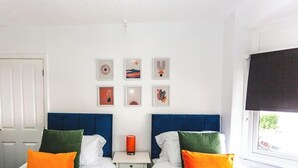 A bedroom with two beds, a nightstand, and six framed pictures on the wall. - 3BR House in Wolves | Ideal for Contractors + Wifi (West Midlands)