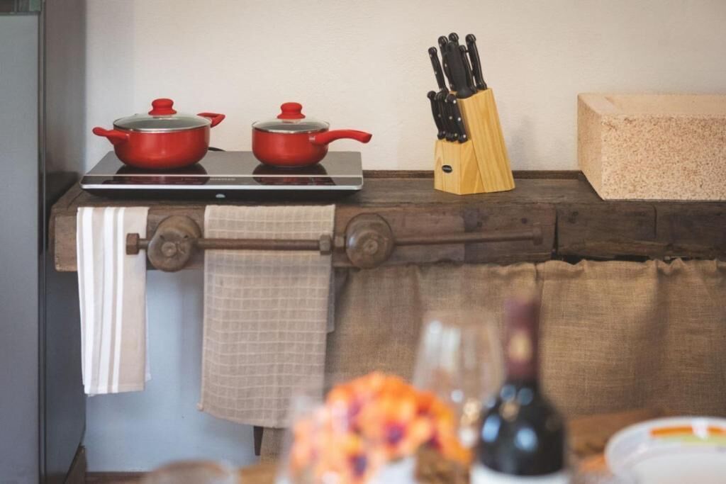 A kitchen counter with two red pots, a knife block, and a bottle.