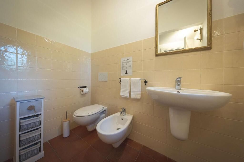 Un baño con inodoro, bidé, lavabo y espejo.
