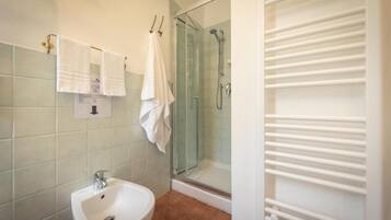 Un bagno con bidet, doccia in vetro e porta asciugamani.