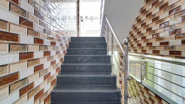 Un escalier au design moderne, flanqué de murs aux motifs décoratifs, menant à un niveau supérieur.