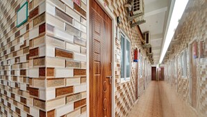 Un couloir aux murs ornés de motifs, une porte en bois et un sol carrelé.
