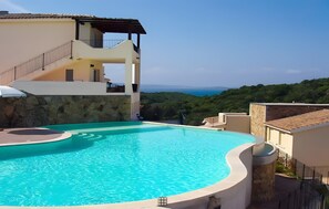 A swimming pool with a stone wall, a staircase, and a view of the sea. - Apartment 'Simone' with Sea View, Shared Pool and Air Conditioning (Arzachena)