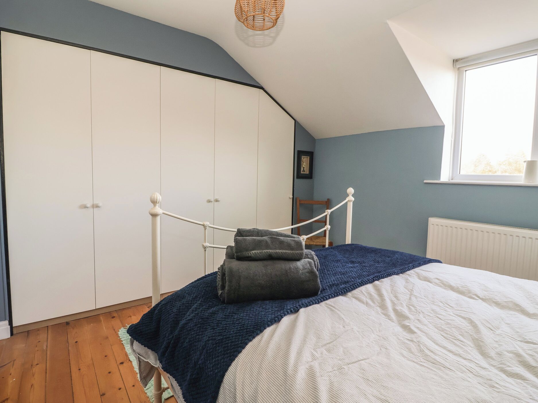 A bedroom with a bed, a wardrobe, a window, and a ceiling light.